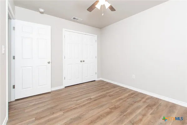 an empty room with wooden floor and windows