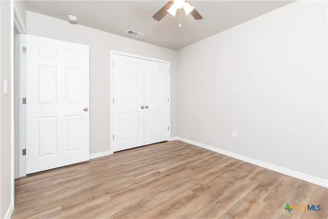 an empty room with wooden floor and windows