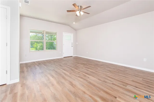 an empty room with windows and a ceiling fan