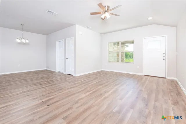 a view of empty room with wooden floor and fan