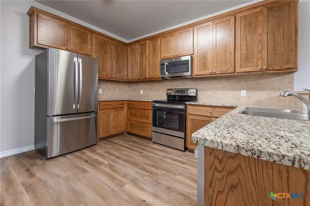 a kitchen with granite countertop wooden cabinets a refrigerator and a sink