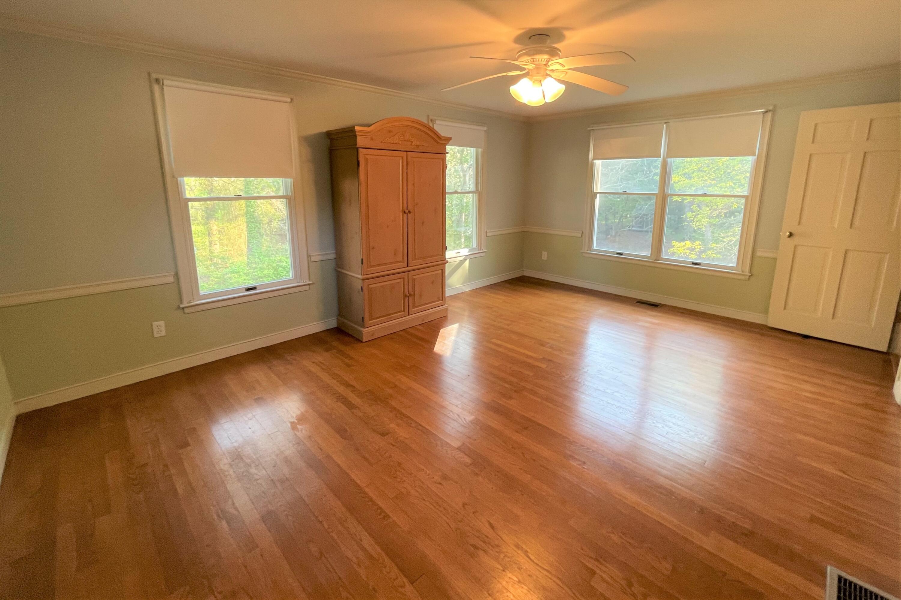 174 Tanglewood Drive Osterville, MA 02655 - Photo 12 of 34 an empty room with wooden floor chandelier fan and windows