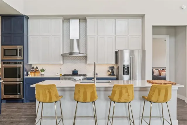 a kitchen with stainless steel appliances granite countertop a table chairs refrigerator and sink