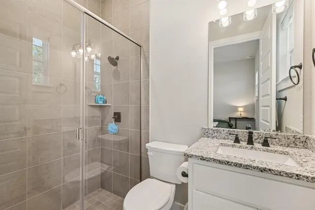 a bathroom with a granite countertop sink toilet a mirror and shower