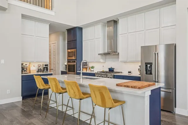 a kitchen with stainless steel appliances granite countertop a dining table chairs and a refrigerator