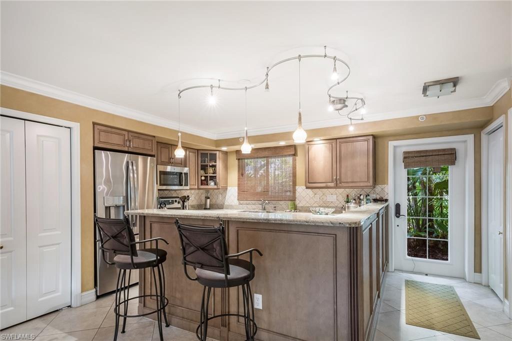 445 3rd Avenue South, Unit 102 Naples, FL 34102 - Photo 3 of 26 a kitchen with stainless steel appliances granite countertop a sink and dishwasher a refrigerator with wooden floor