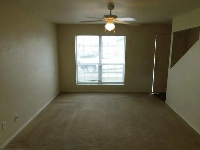 an empty room with windows and fan