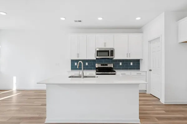 a kitchen with stainless steel appliances a sink a stove a microwave a sink a refrigerator and cabinets