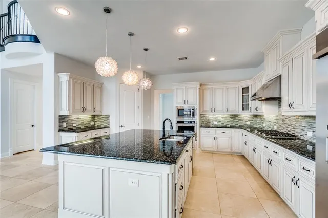 a kitchen with granite countertop a sink and white cabinets