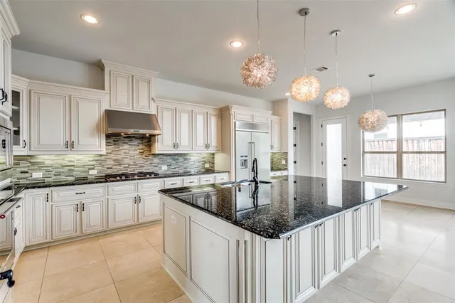a kitchen with granite countertop a sink a counter top space cabinets and stainless steel appliances