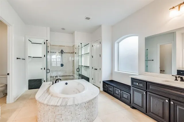 a bathroom with a sink double vanity granite tub shower and a mirror