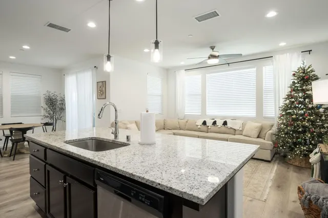 a kitchen with granite countertop a sink a counter top space and living room view