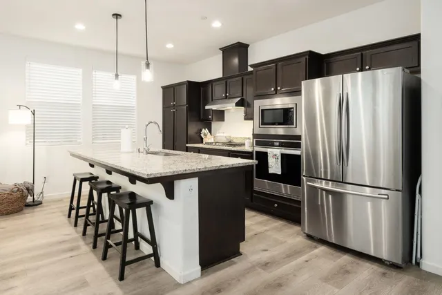a kitchen with kitchen island stainless steel appliances a sink and a refrigerator
