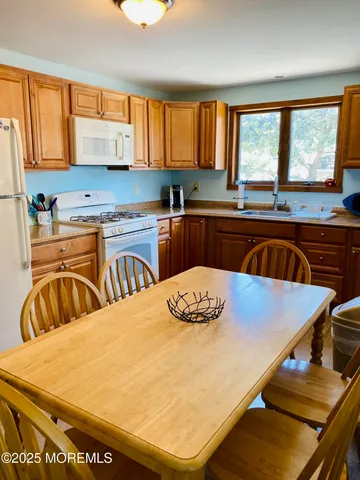 a kitchen with stainless steel appliances granite countertop a stove a sink a dining table and chairs