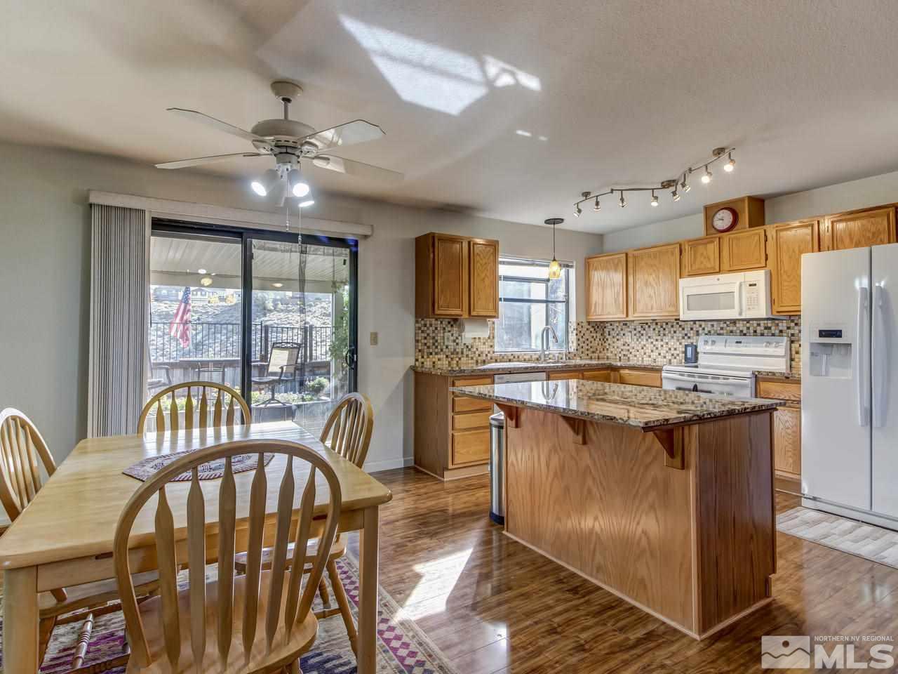 1040 Backer Way Reno, NV 89523 - Photo 8 of 25 a kitchen with stainless steel appliances granite countertop a stove top oven a refrigerator a sink dishwasher a dining table and chairs with wooden floor