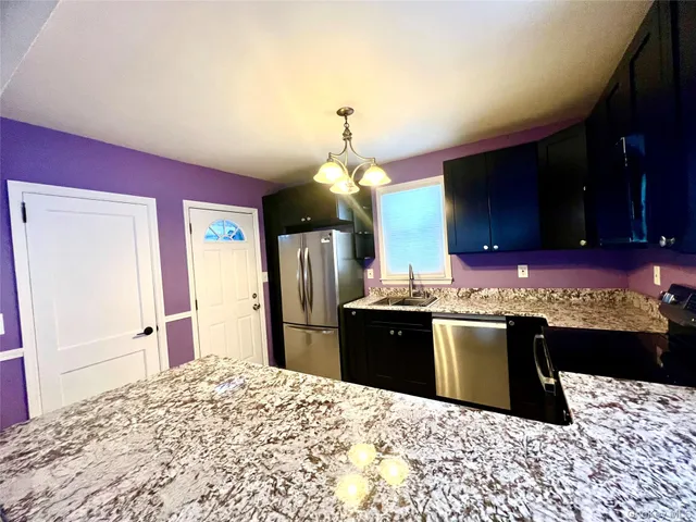 a kitchen with stainless steel appliances kitchen island granite countertop cabinets a sink and a refrigerator