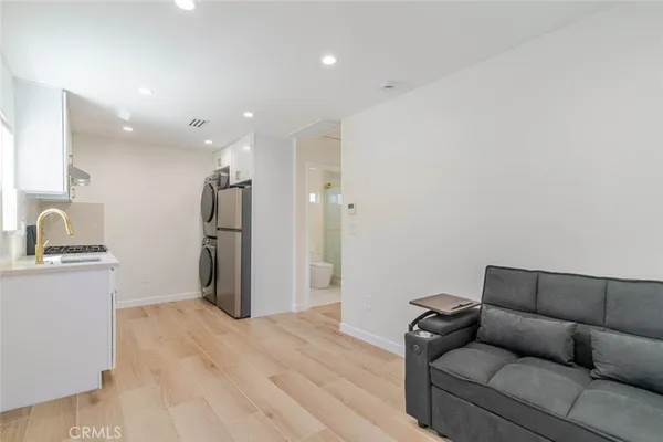 a living room with stainless steel appliances kitchen island furniture and a wooden floor