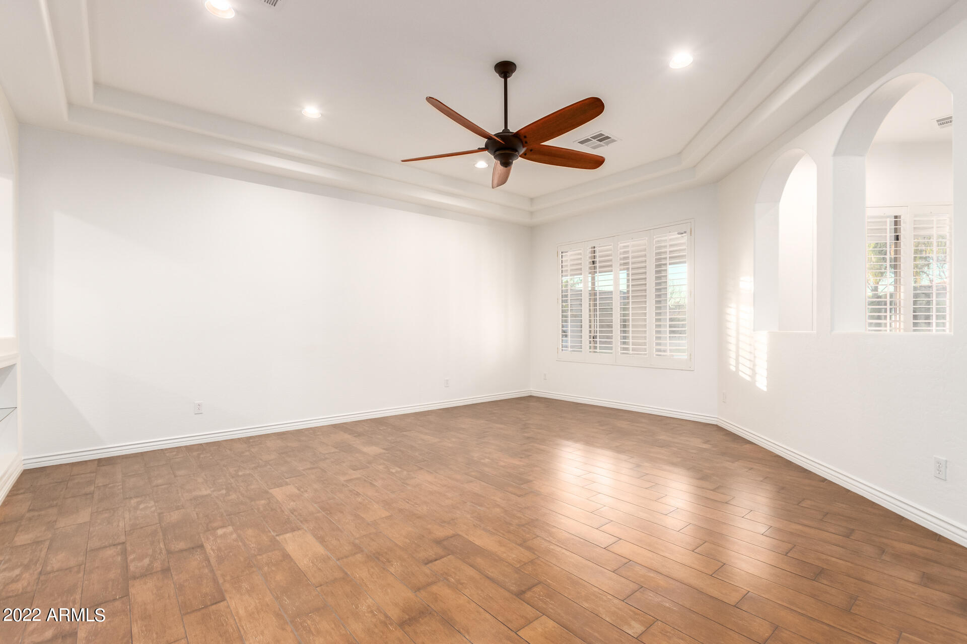 4584 East Reins Road Gilbert, AZ 85297 - Photo 9 of 80 an empty room with wooden floor ceiling fan and windows