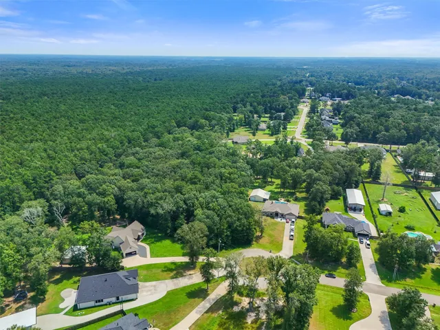 an aerial view of residential house with outdoor space and trees all around