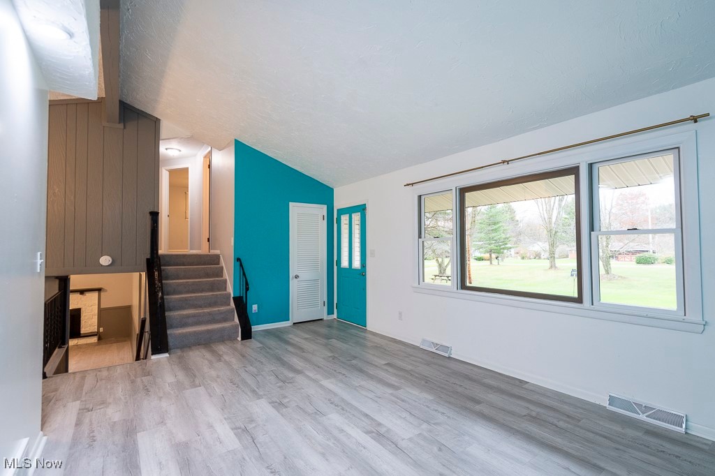11819 Sheldon Road Mantua, OH 44255 - Photo 4 of 46 Unfurnished living room with lofted ceiling, a textured ceiling, and luxury vinyl plank flooring
