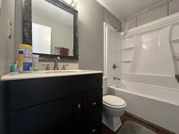 a bathroom with a sink a toilet a mirror and shower