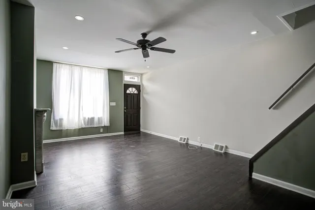an empty room with wooden floor fan and windows