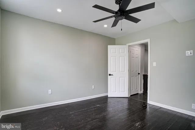 an empty room with wooden floor and ceiling fan