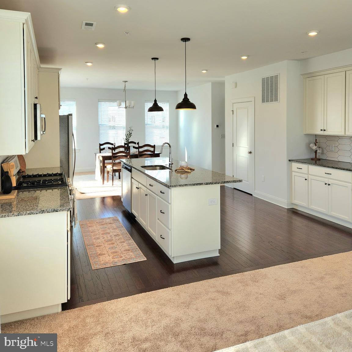 a large kitchen with stainless steel appliances kitchen island granite countertop a sink and a stove