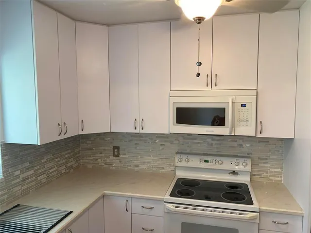 a kitchen with granite countertop white cabinets and white appliances