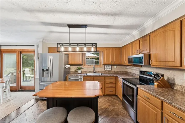 a kitchen with kitchen island granite countertop wooden cabinets a stove top oven a sink and dishwasher
