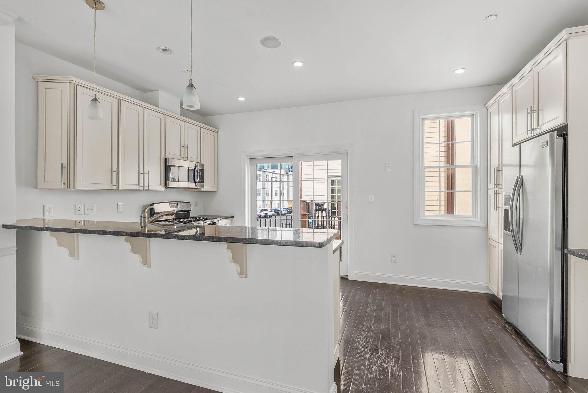 1015 North 3rd Street, Unit H Philadelphia, PA 19123 - Photo 6 of 27 a kitchen with stainless steel appliances granite countertop a refrigerator a sink dishwasher a stove and white countertops with wooden floor