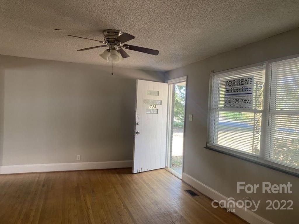 725 Tom Sadler Road Charlotte, NC 28214 - Photo 3 of 9 an empty room with wooden floor fan and windows