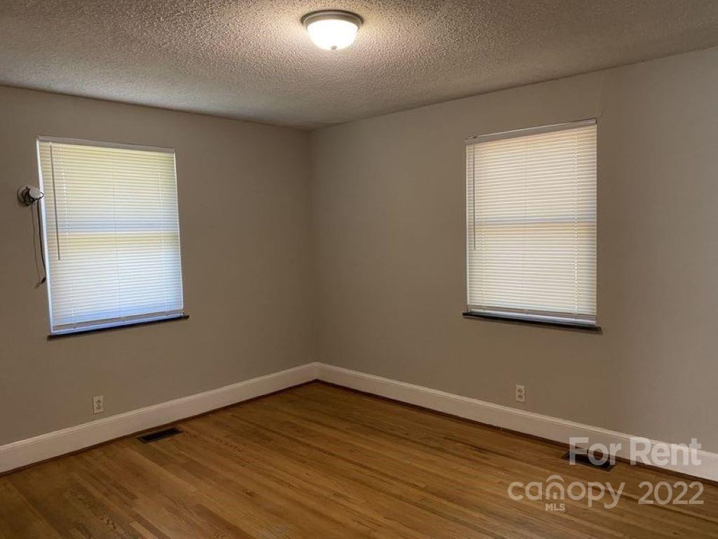 725 Tom Sadler Road Charlotte, NC 28214 - Photo 4 of 9 an empty room with wooden floor and windows