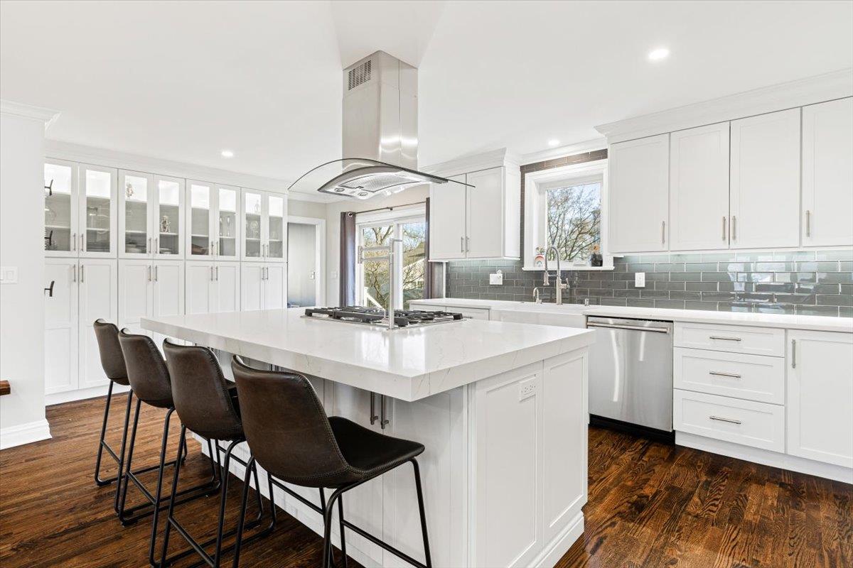 Kitchen featuring a center island, appliances with stainless steel finishes, island exhaust hood, dark wood-style floors, and a sink