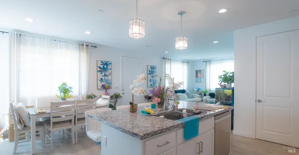 a living room with furniture potted plant and kitchen view