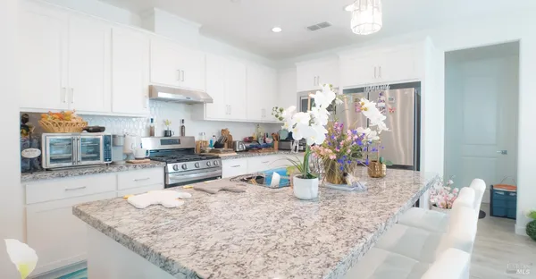 a dining room with stainless steel appliances kitchen island granite countertop a refrigerator a sink a stove a dining table and chairs