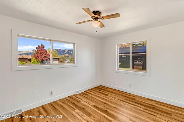 a view of an empty room with window and a chandelier fan