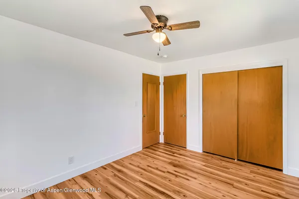 a view of an empty room with window and chandelier fan