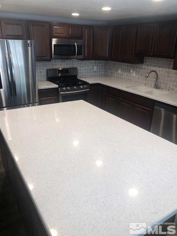 1885 Wilder Street Reno, NV 89512 - Photo 4 of 19 a kitchen with granite countertop a sink a stove a refrigerator and cabinets