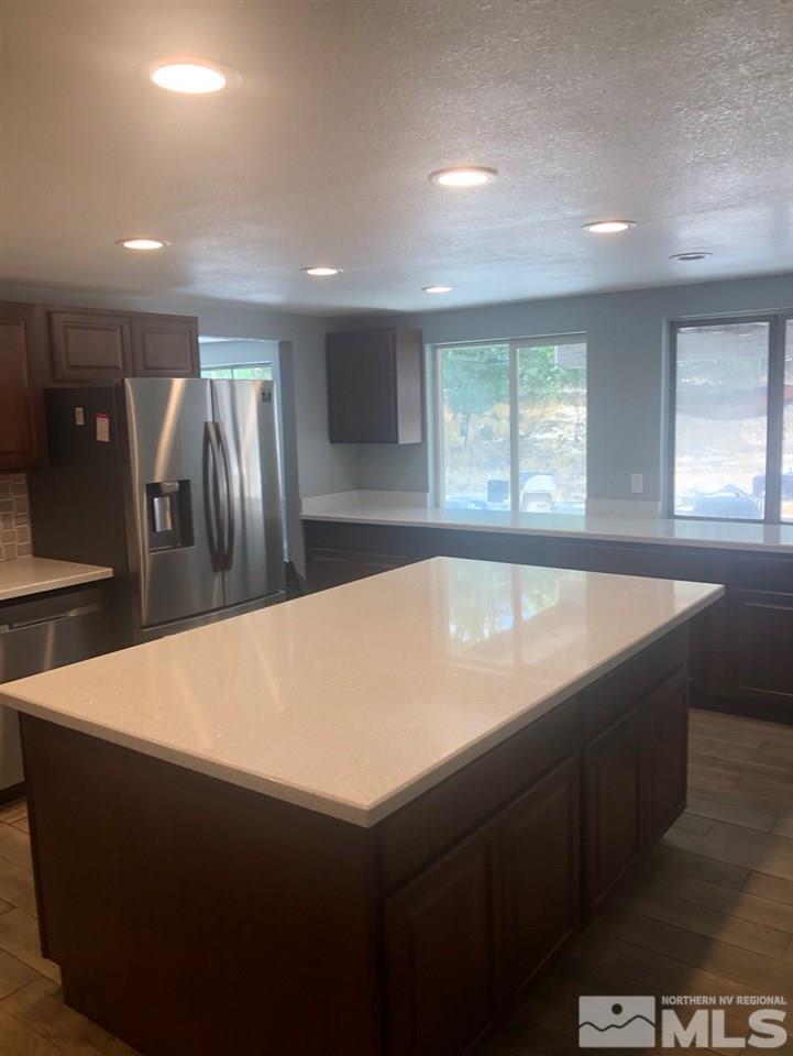 1885 Wilder Street Reno, NV 89512 - Photo 9 of 19 a large kitchen with kitchen island a sink dishwasher a refrigerator and black white cabinets next to a window
