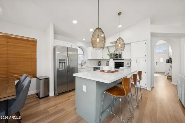 a kitchen with stainless steel appliances a dining table chairs and wooden floor