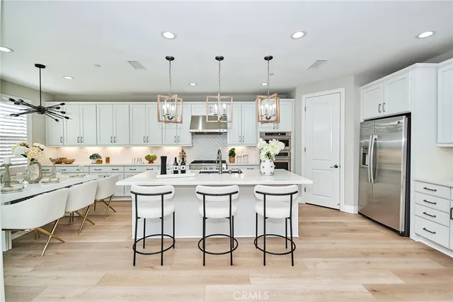 a kitchen with stainless steel appliances kitchen island granite countertop a table chairs refrigerator and sink