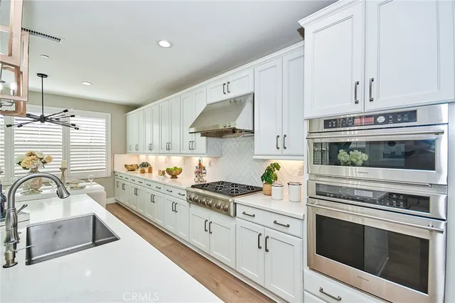 a kitchen with stainless steel appliances white cabinets and a stove a sink