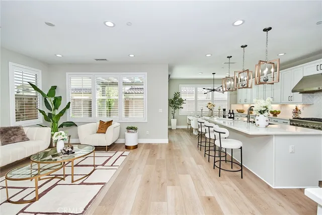 a kitchen with stainless steel appliances granite countertop a stove a sink dishwasher a dining table and chairs with wooden floor