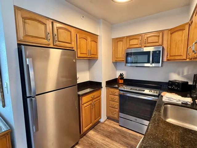 a kitchen with stainless steel appliances granite countertop a refrigerator a microwave a sink and cabinets