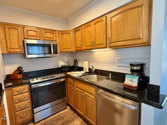 a kitchen with stainless steel appliances granite countertop a sink stove and microwave