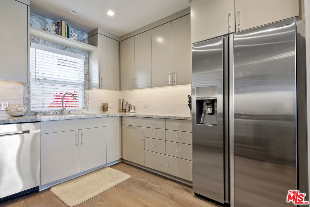 18147 Coastline Drive, Unit 3 Malibu, CA 90265 - Photo 11 of 40 a kitchen with granite countertop a refrigerator and white cabinets