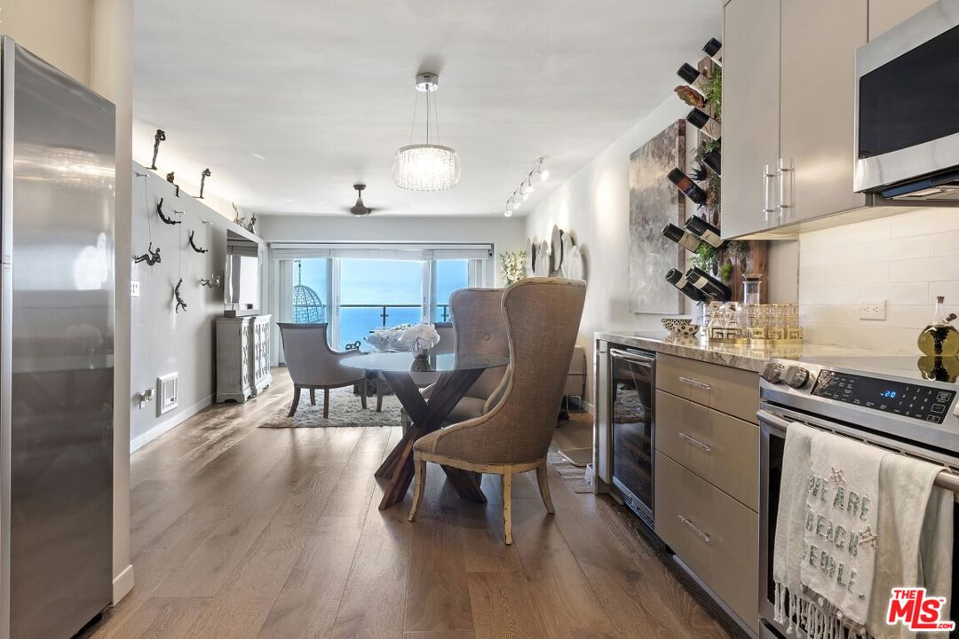 18147 Coastline Drive, Unit 3 Malibu, CA 90265 - Photo 12 of 40 a kitchen with stainless steel appliances granite countertop a table chairs refrigerator and microwave