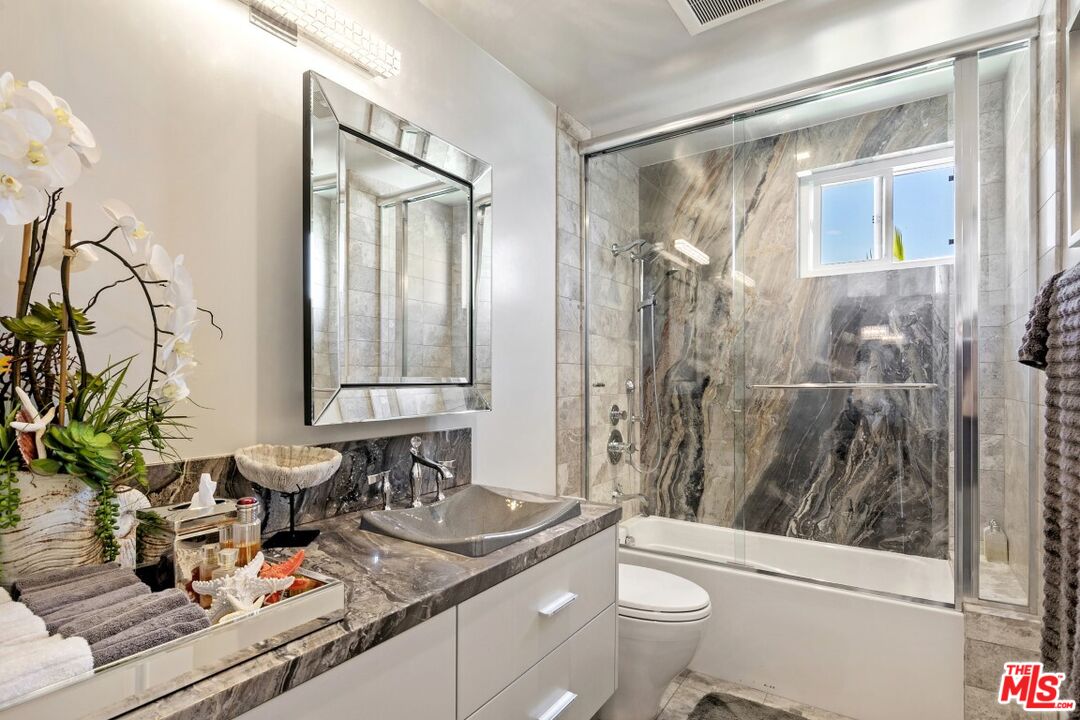 18147 Coastline Drive, Unit 3 Malibu, CA 90265 - Photo 29 of 40 a bathroom with a granite countertop sink a mirror a vanity and a shower