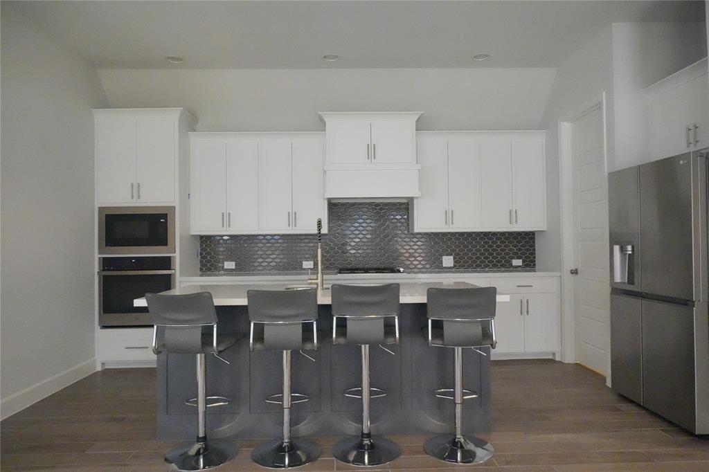 4115 Hudson Street Fate, TX 75087 - Photo 7 of 24 a white kitchen with a stove a refrigerator and white cabinets